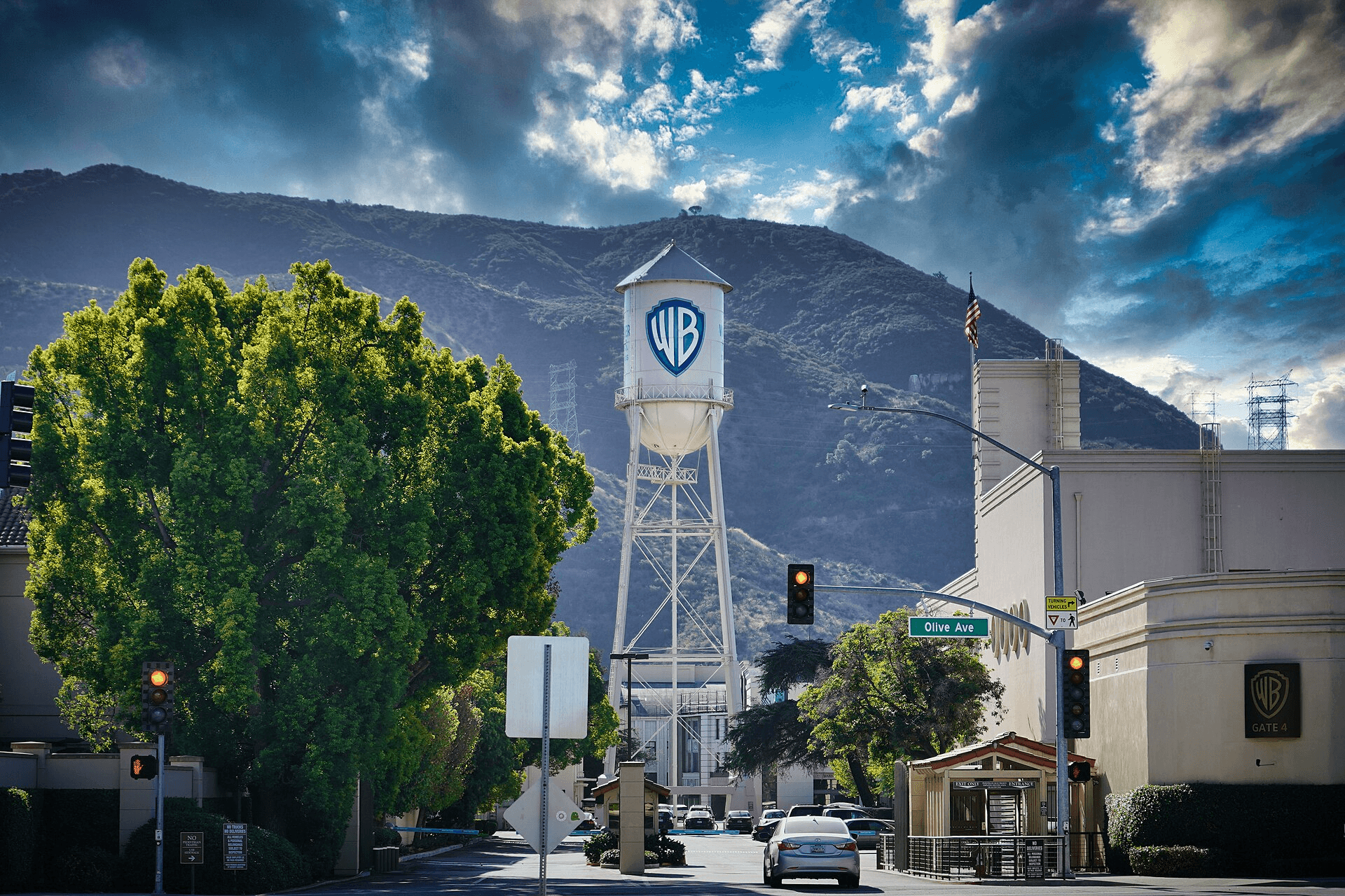 Iconic Warner Bros. water tower stands before mountains under a dramatic, cloudy blue sky.